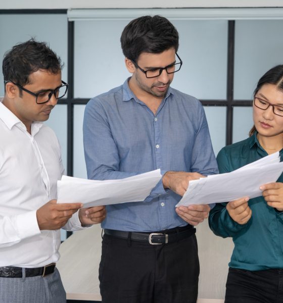 Multiethnic business team analyzing financial reports. Smart experts presenting papers to group leader. Teamwork and analysis concept